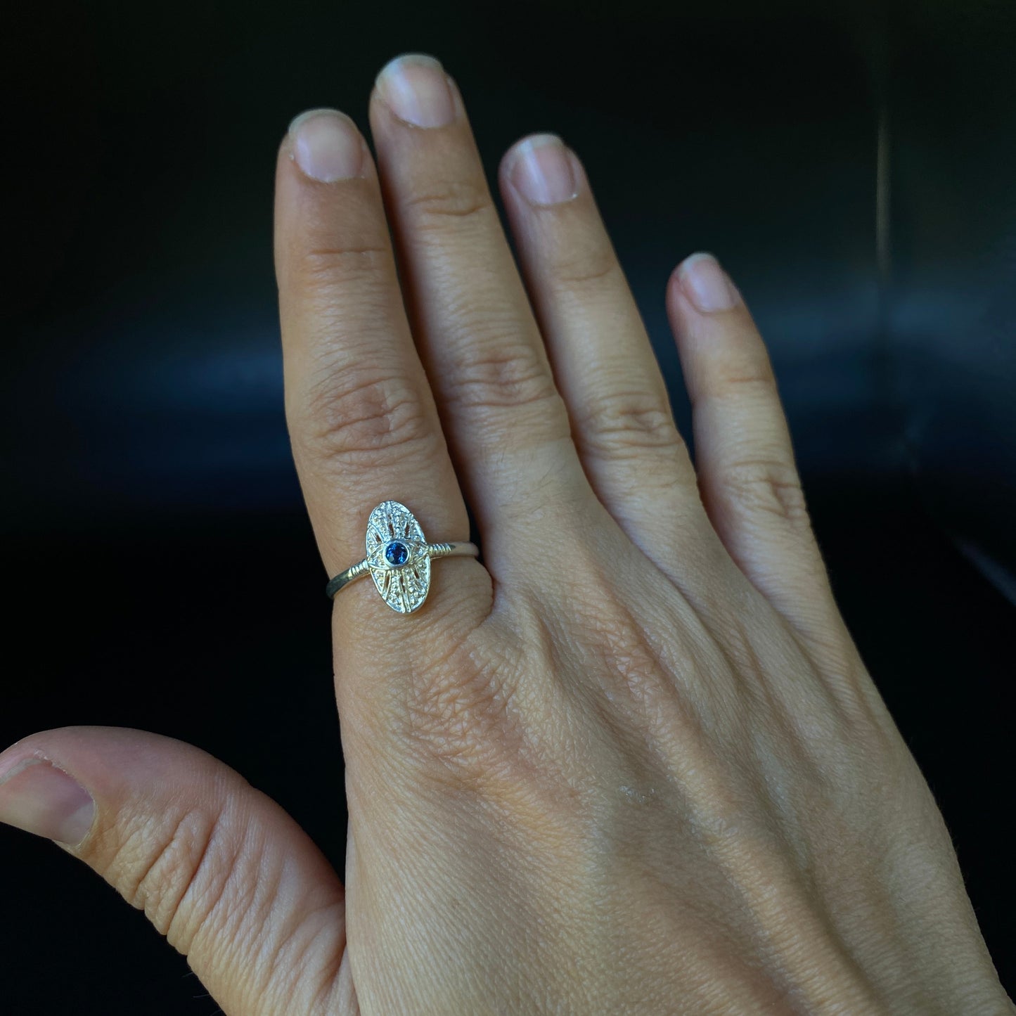 Hand wearing a ring with a dark background