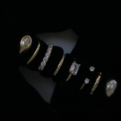 A set of gold rings with diamonds displayed on a black velvet ring stand against a black background.