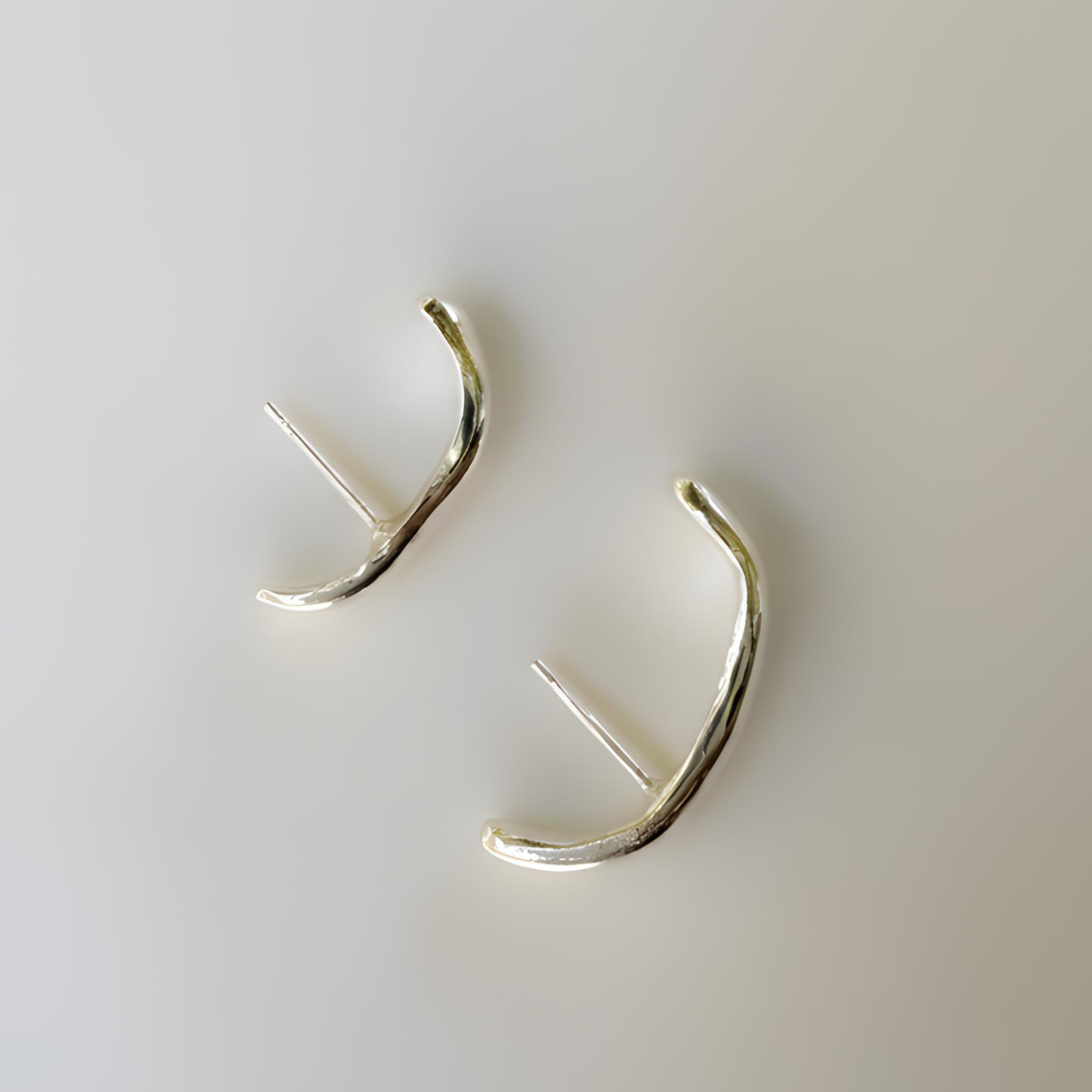 Silver cuff earrings on a light gray background
