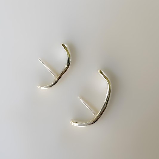 Silver cuff earrings on a light gray background