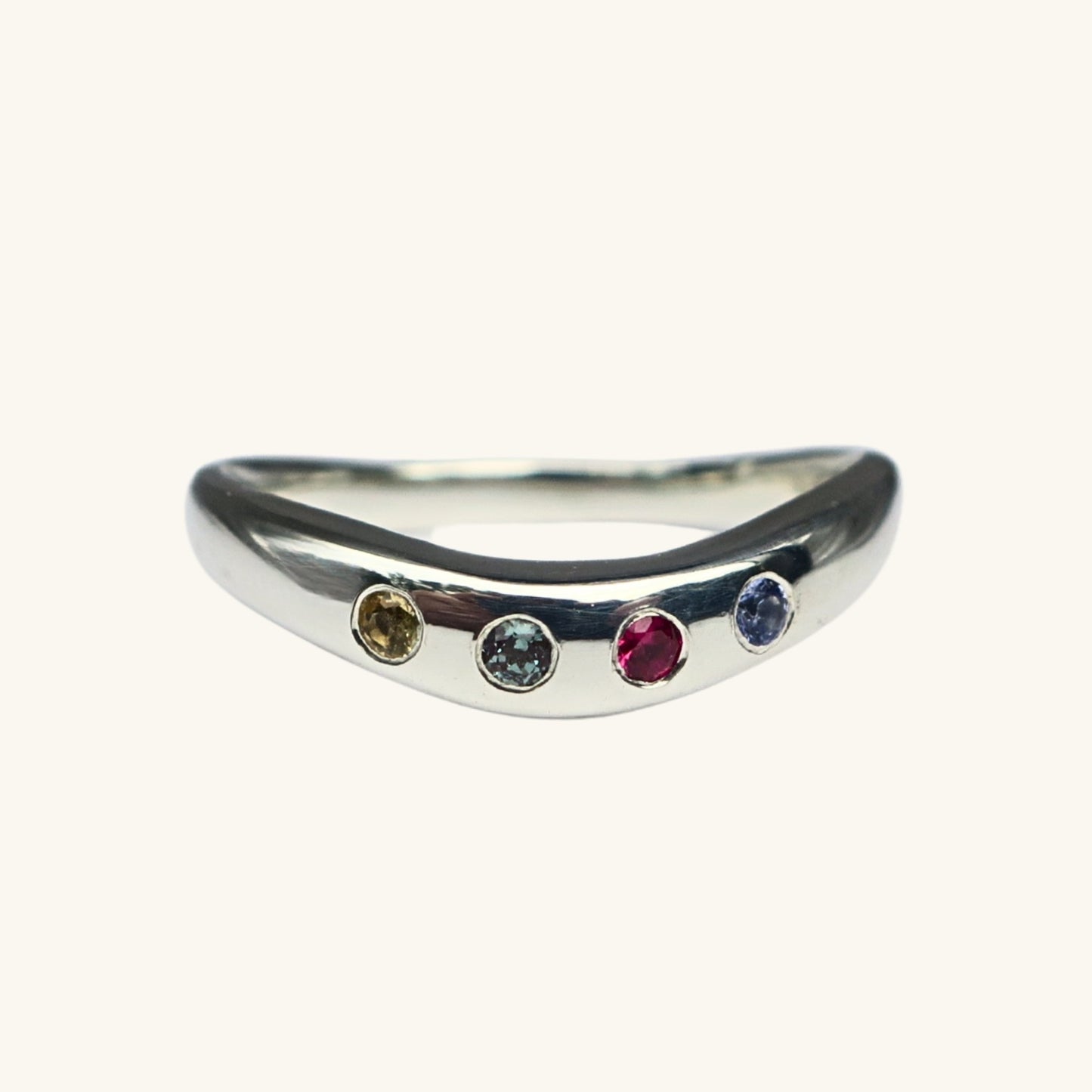 Silver ring with four gemstones on a white background