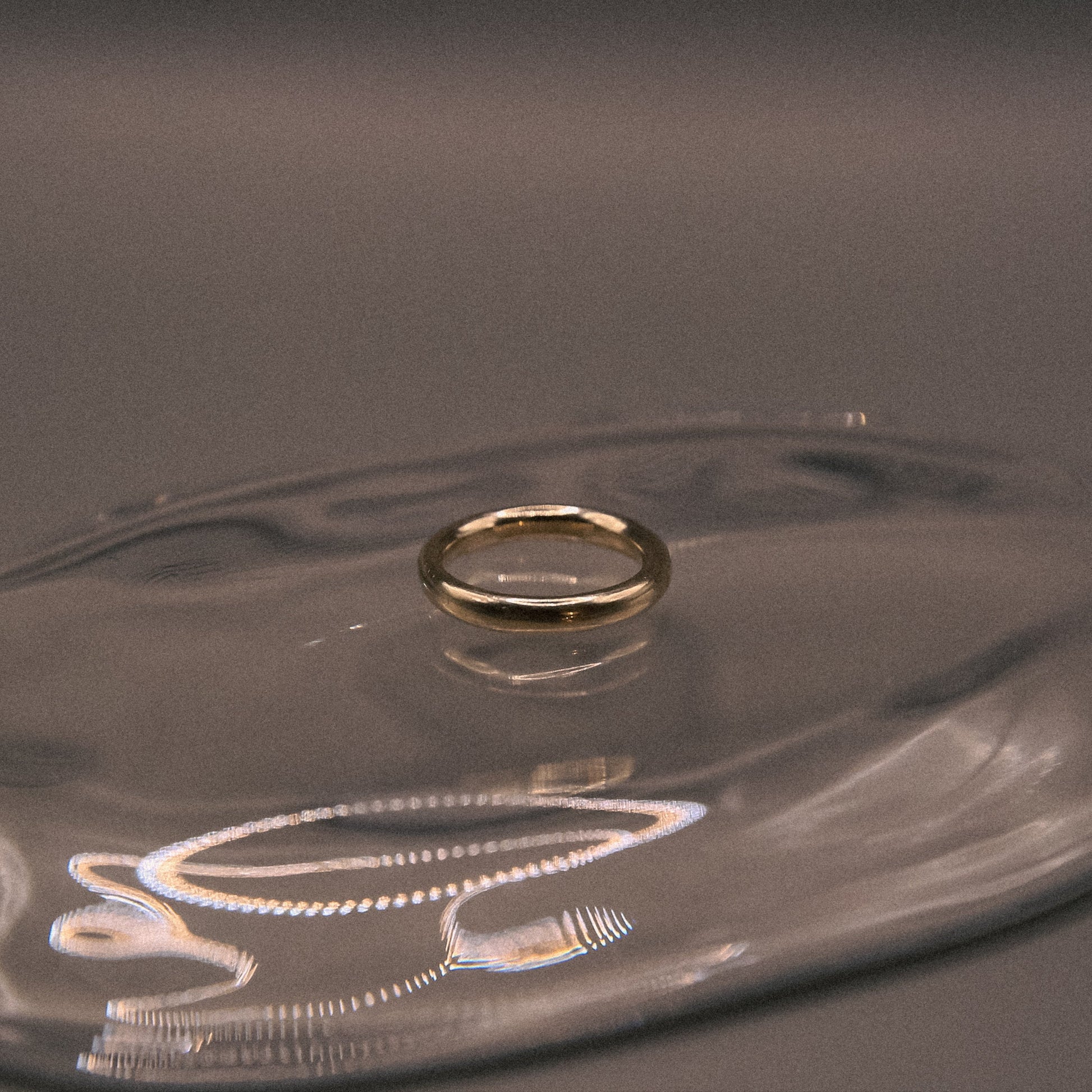 Gold ring on a clear glass surface with a dark background