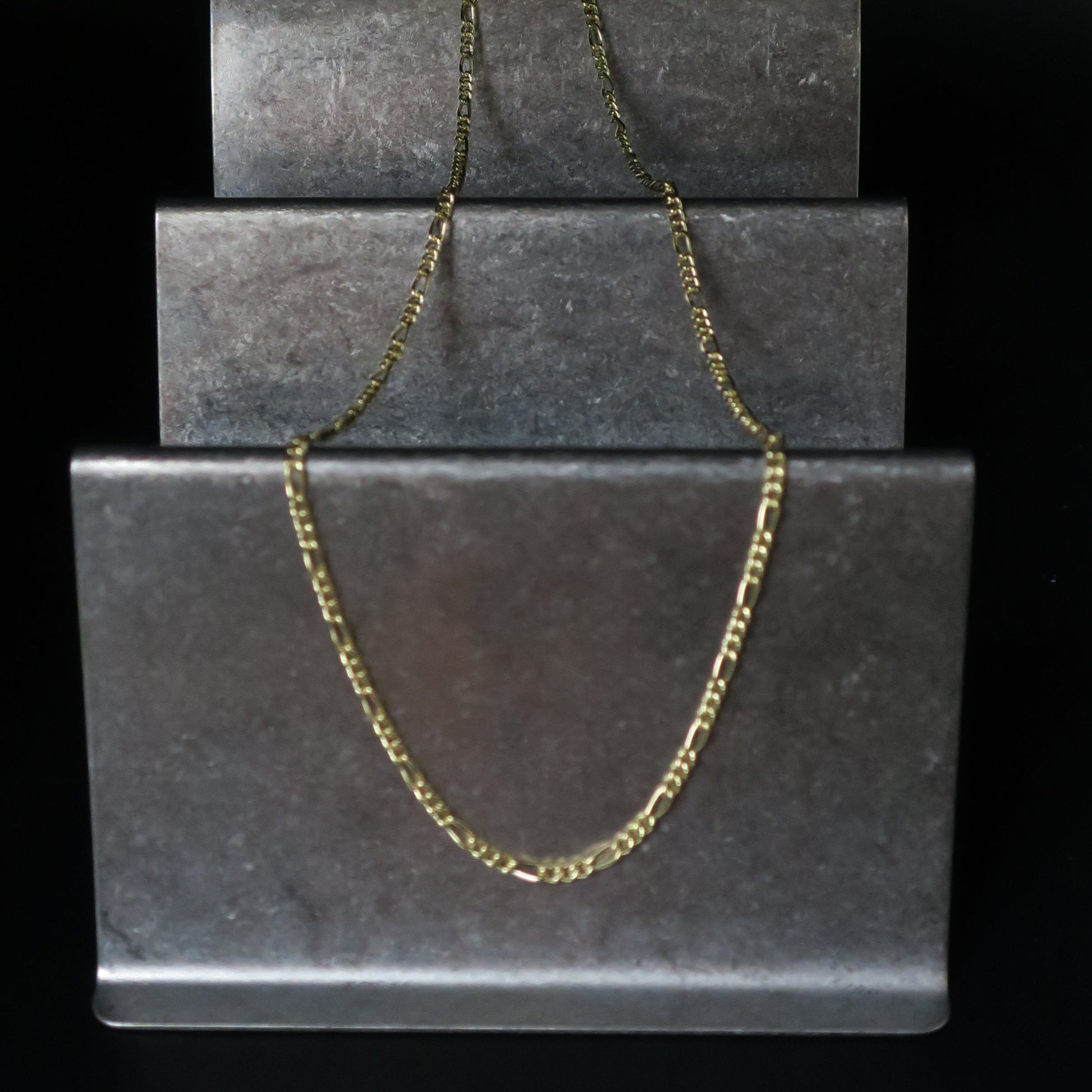 Gold chain on a black jewelry box with a black background