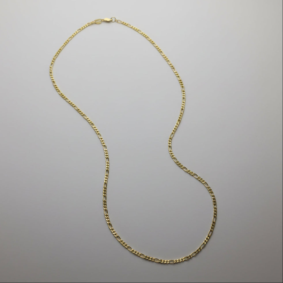 Gold chain necklace on a gray background