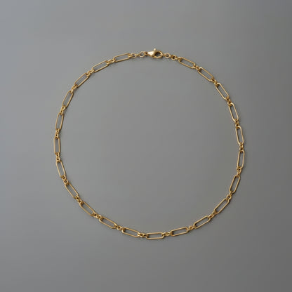 Gold chain necklace on a gray background