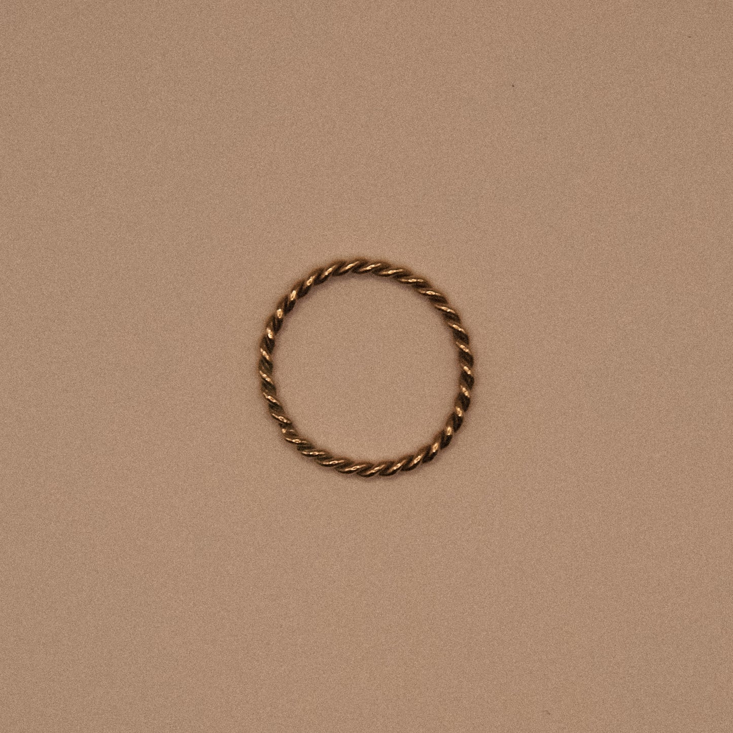 Twisted gold ring on a beige background