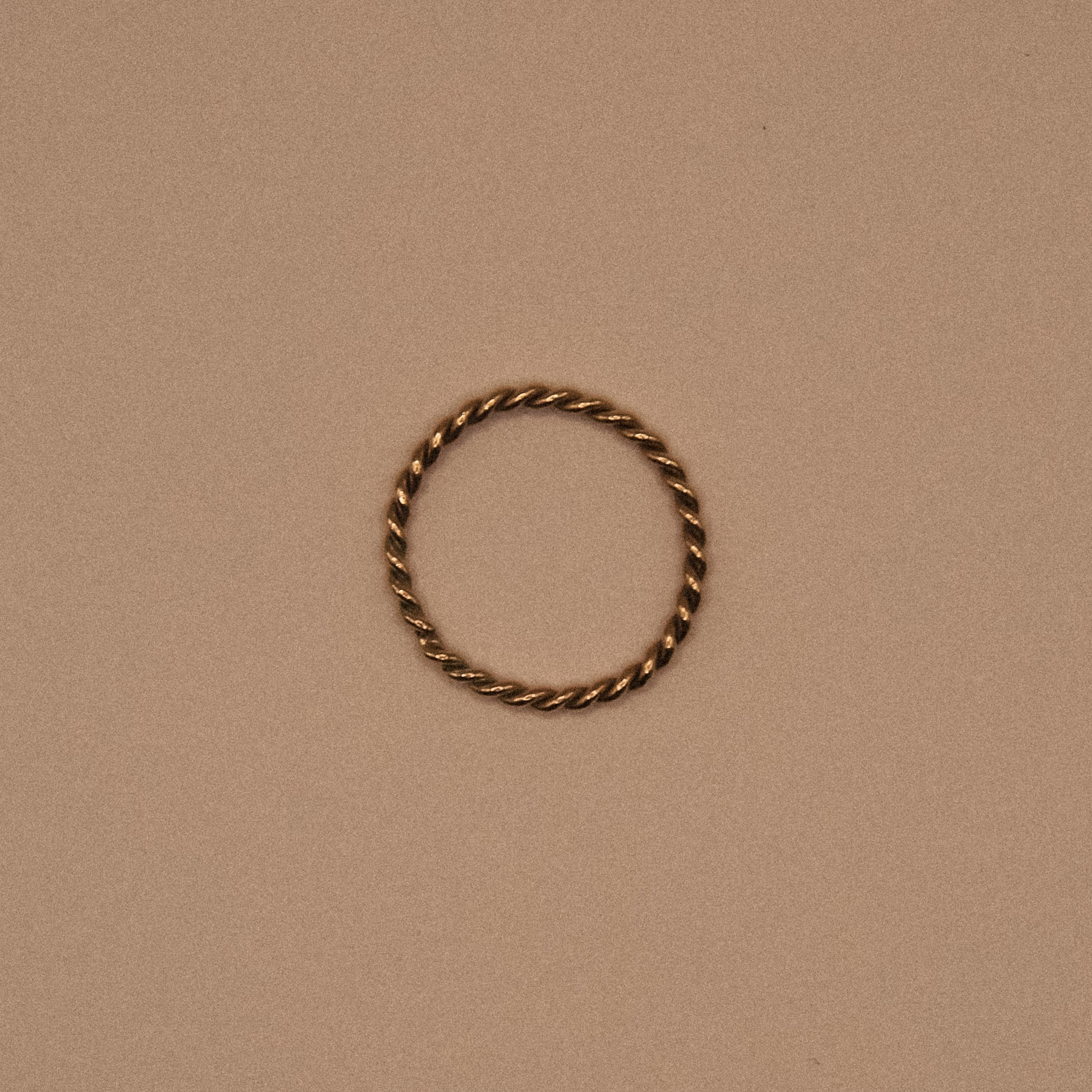 Twisted gold ring on a beige background