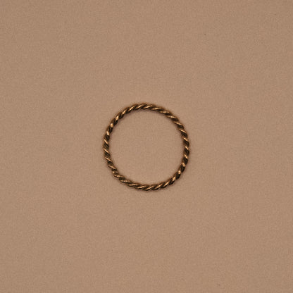 Twisted gold ring on a beige background