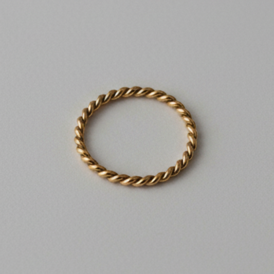 Gold ring with a twisted design on a gray background