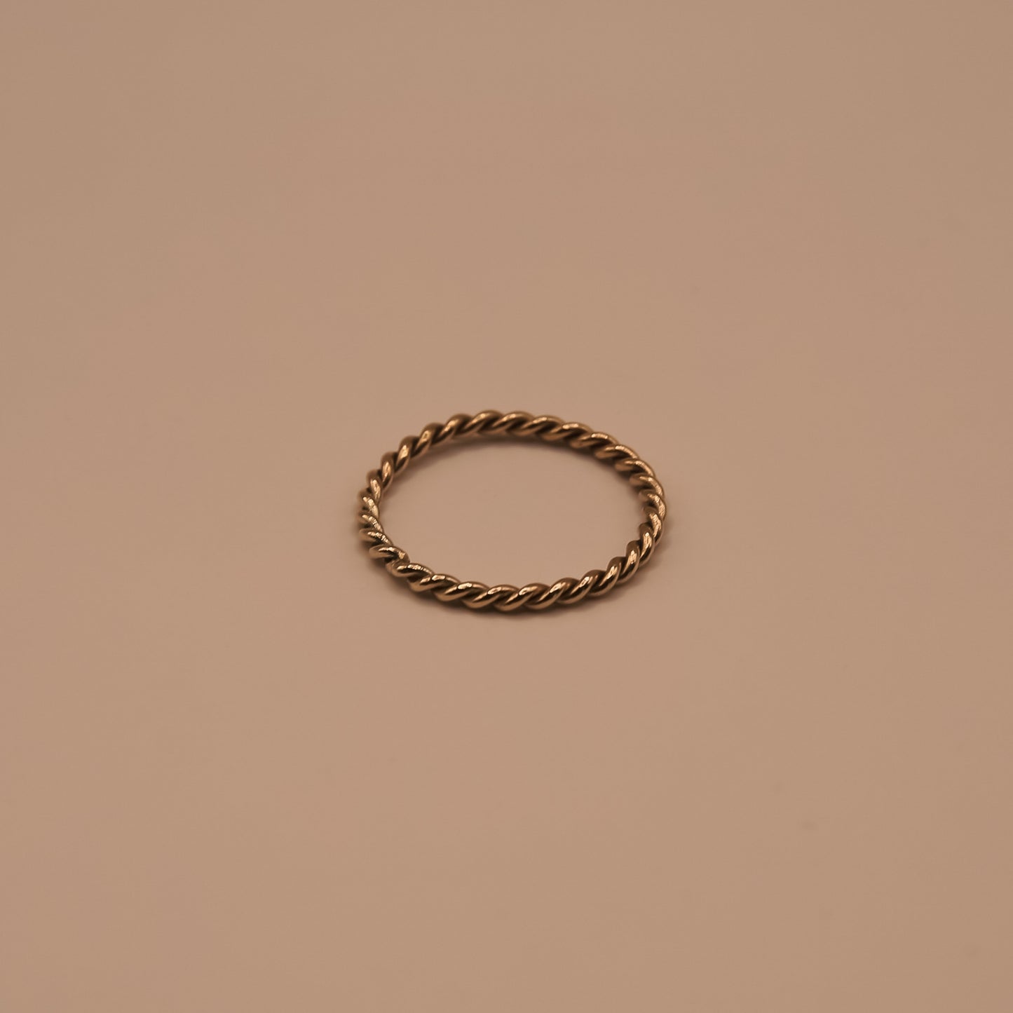 Bronze twisted ring on a beige background