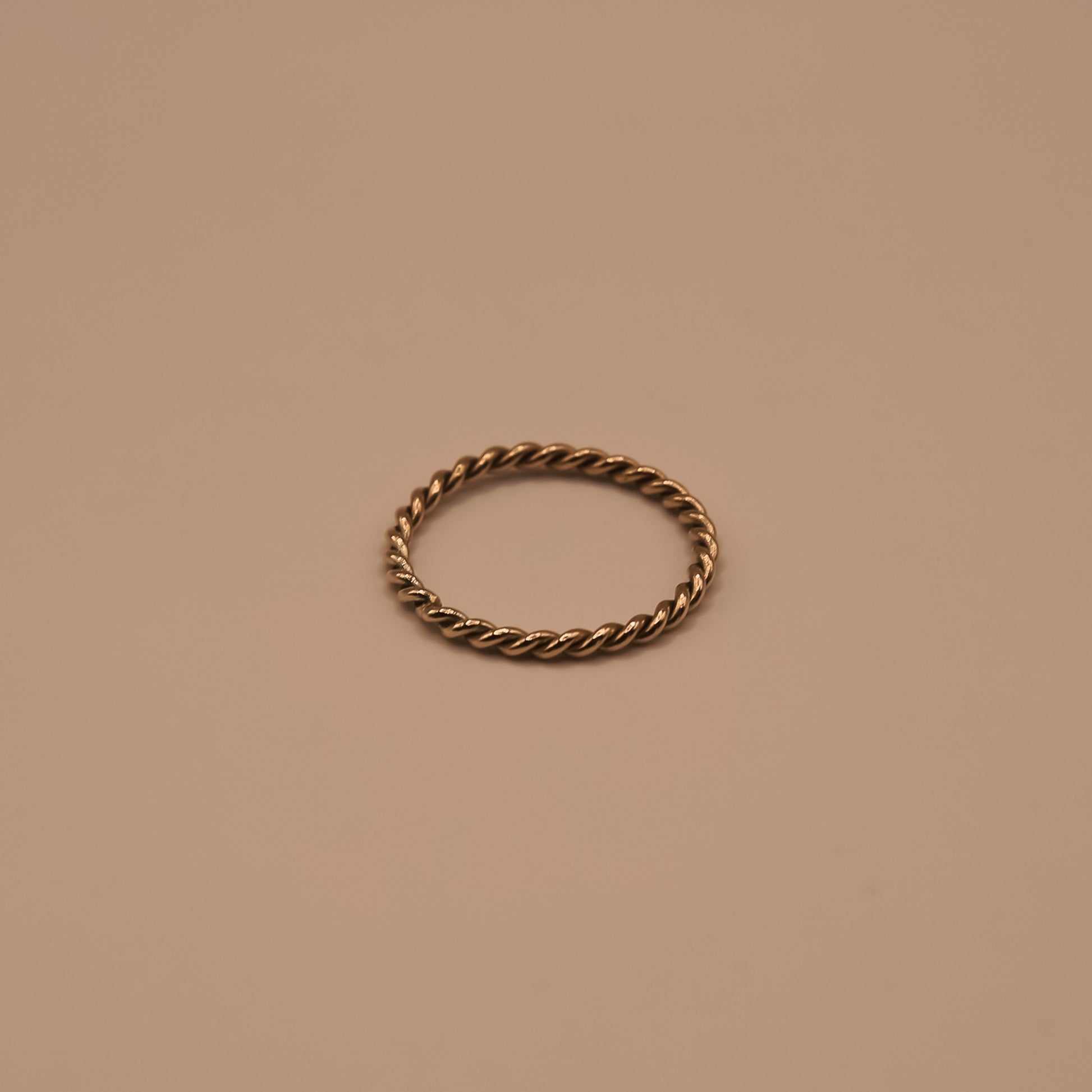 Bronze twisted ring on a beige background