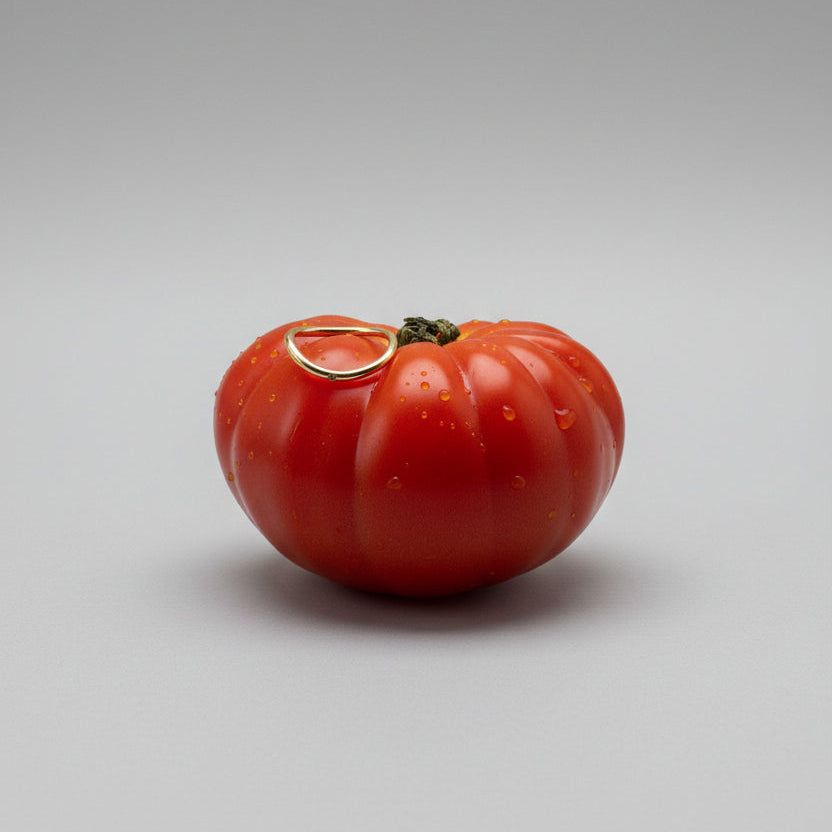 Red tomato with a gold ring on a studio background