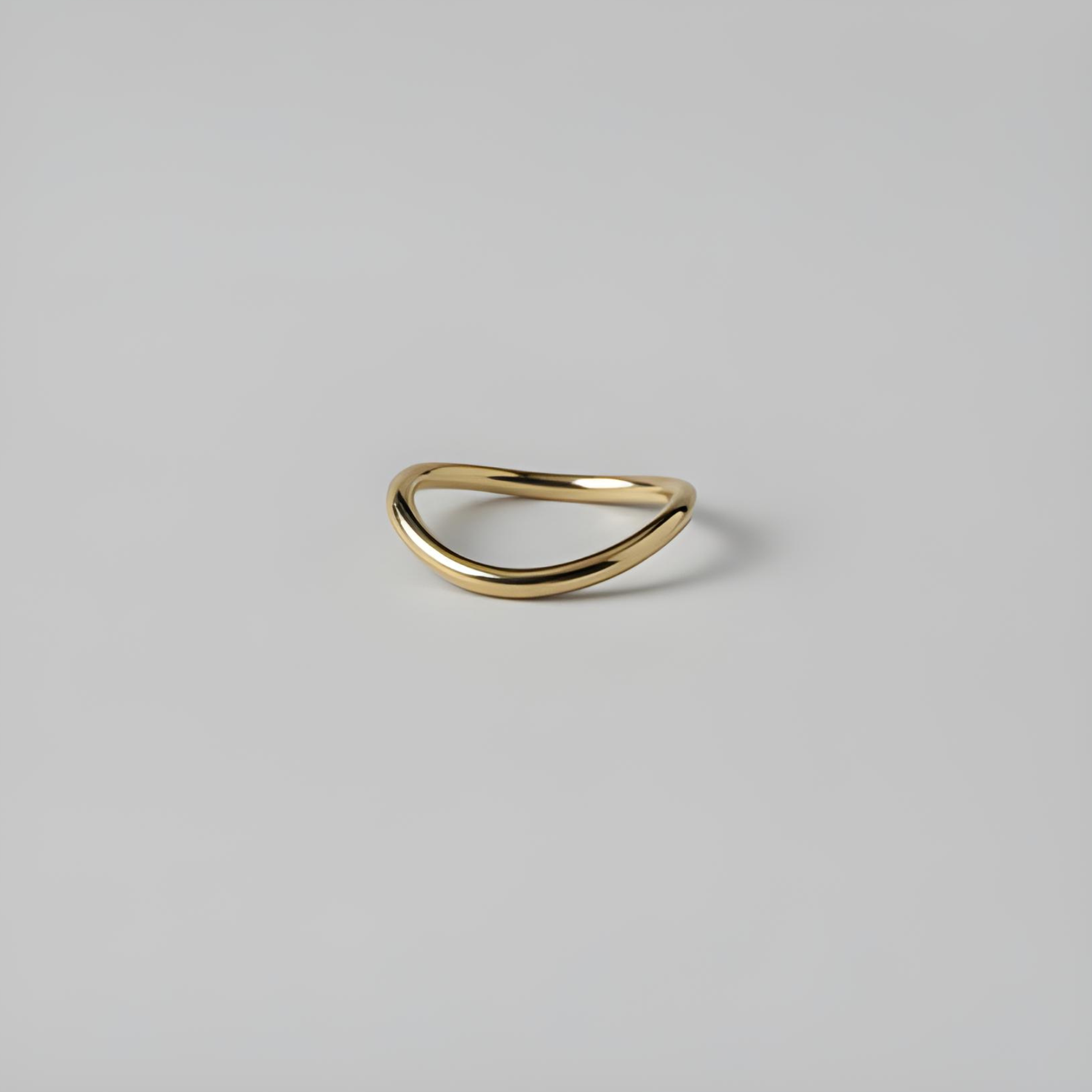 Gold ring with a curved design on a light grey background