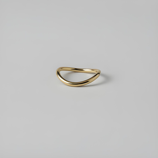 Gold ring with a curved design on a light grey background