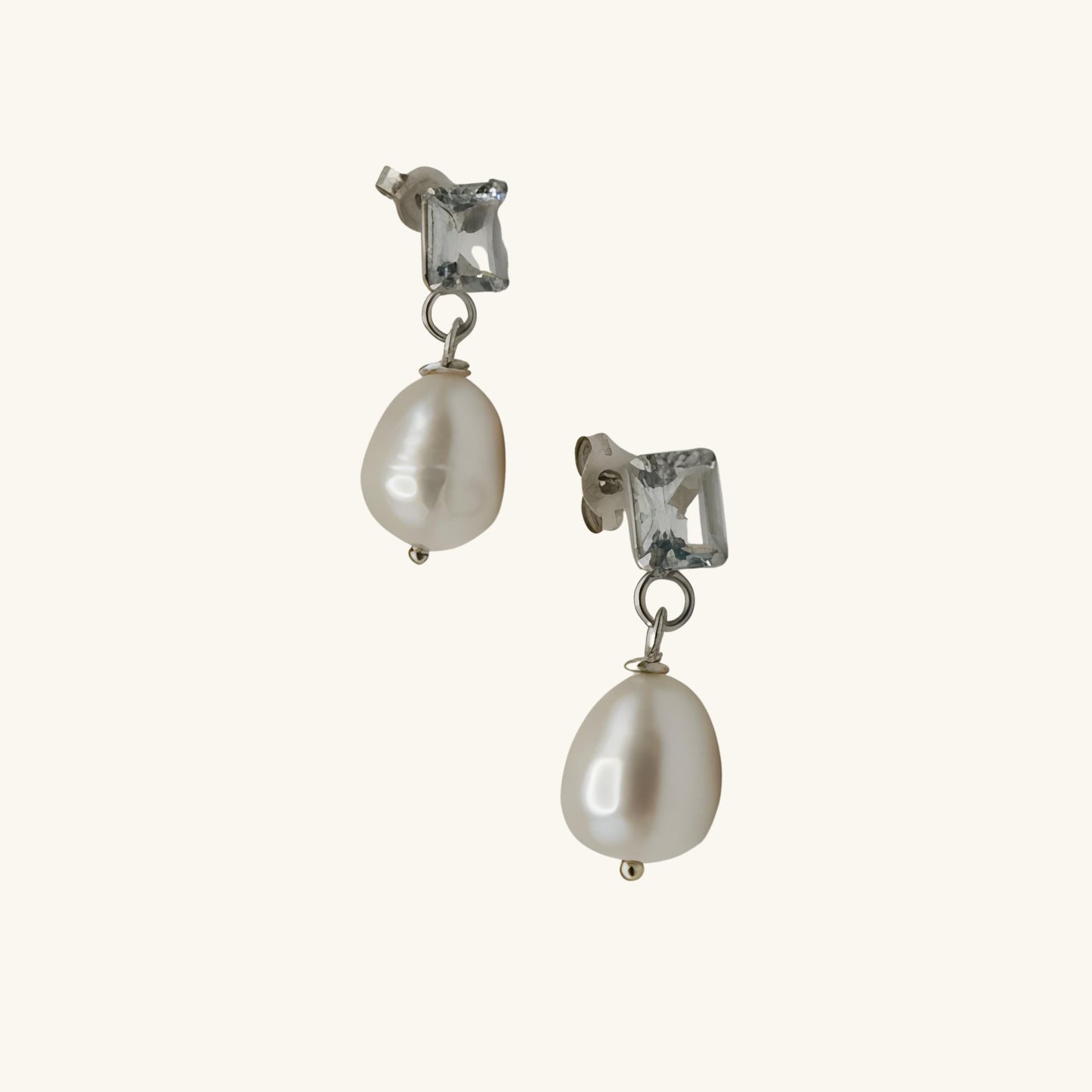 Pair of pearl earrings with clear gemstones on a white background