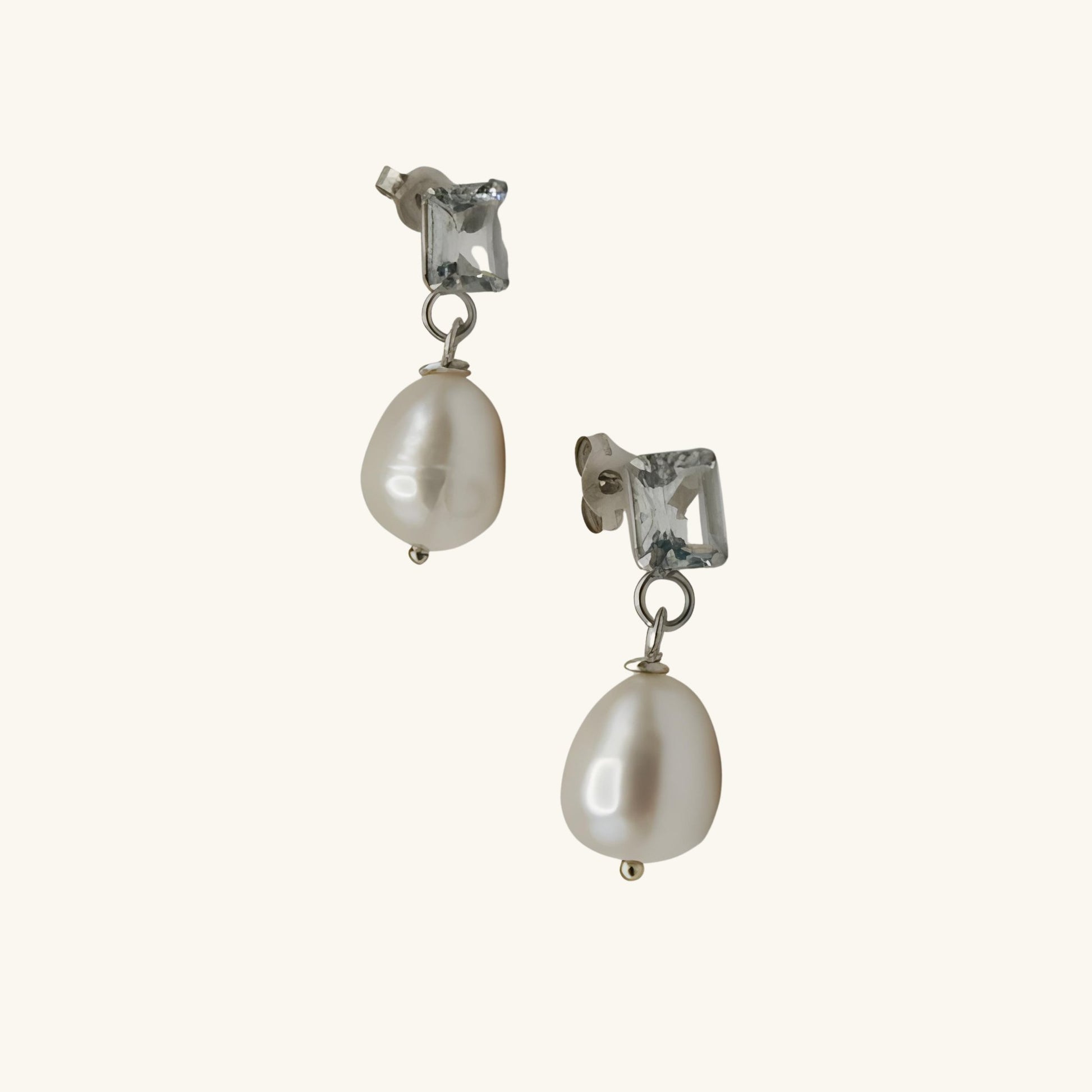 Pair of pearl earrings with clear gemstones on a white background