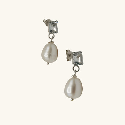 Pair of pearl earrings with clear gemstones on a white background