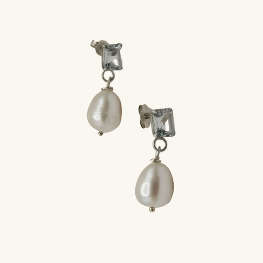 Pair of pearl earrings with clear gemstones on a white background