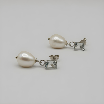 Pair of pearl and gem earrings on a light gray background