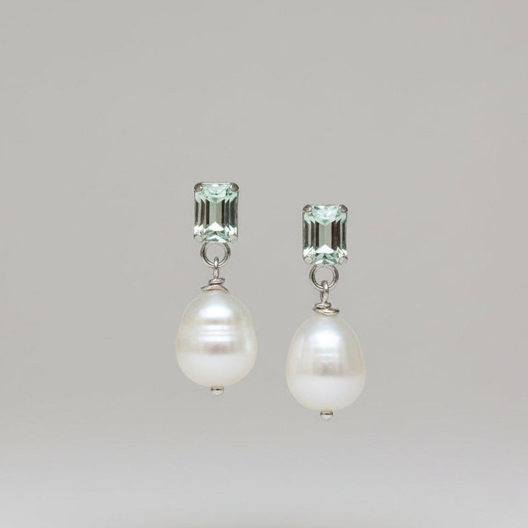 A pair of pearl and quartz stud earrings on a greybackground, with the pearls white and the quartzes cut to rectangular shapes.