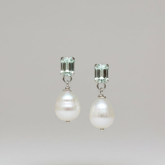 A pair of pearl and quartz stud earrings on a greybackground, with the pearls white and the quartzes cut to rectangular shapes.