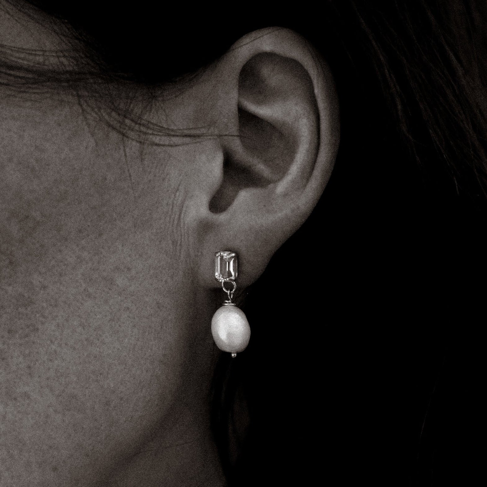 Pearl earring worn by a person against a dark background