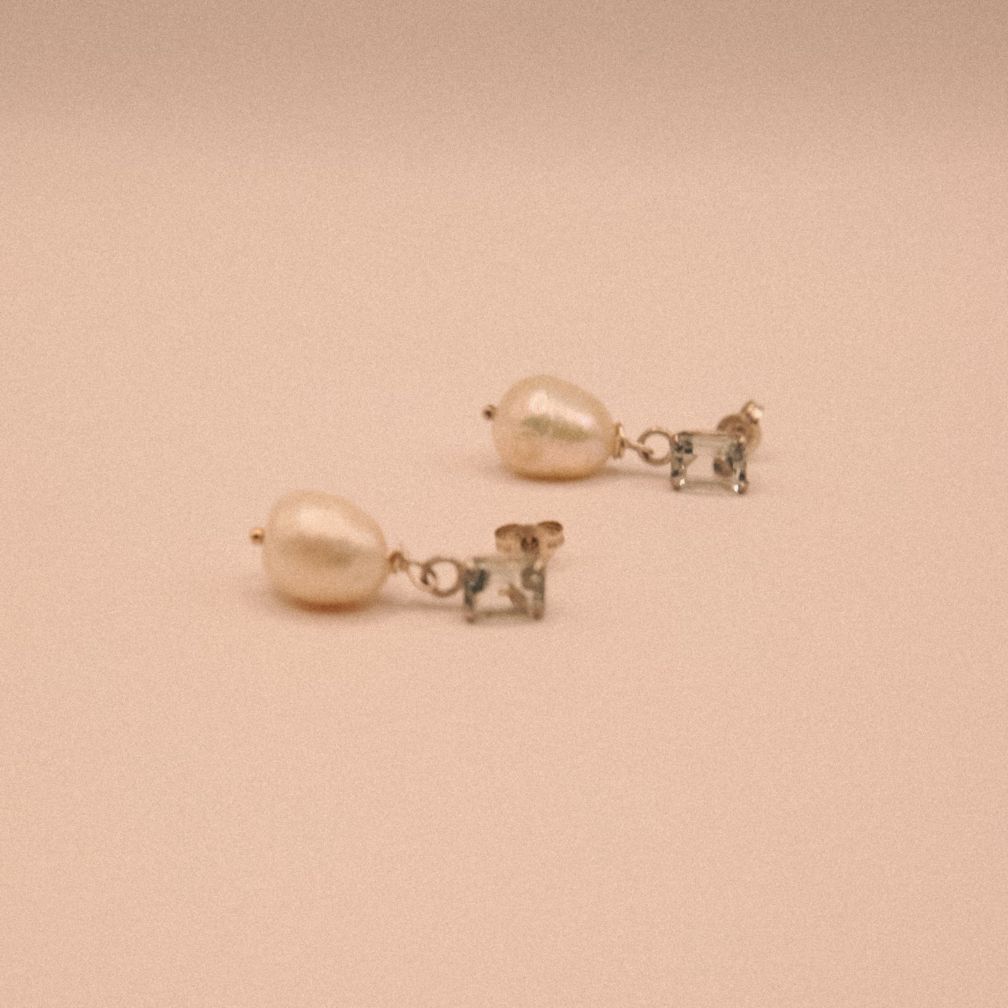 Pair of pearl earrings on a beige background