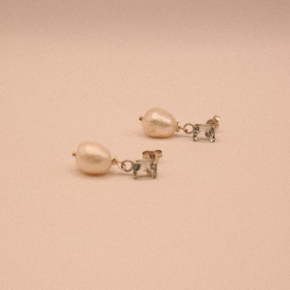 Pair of pearl earrings on a beige background