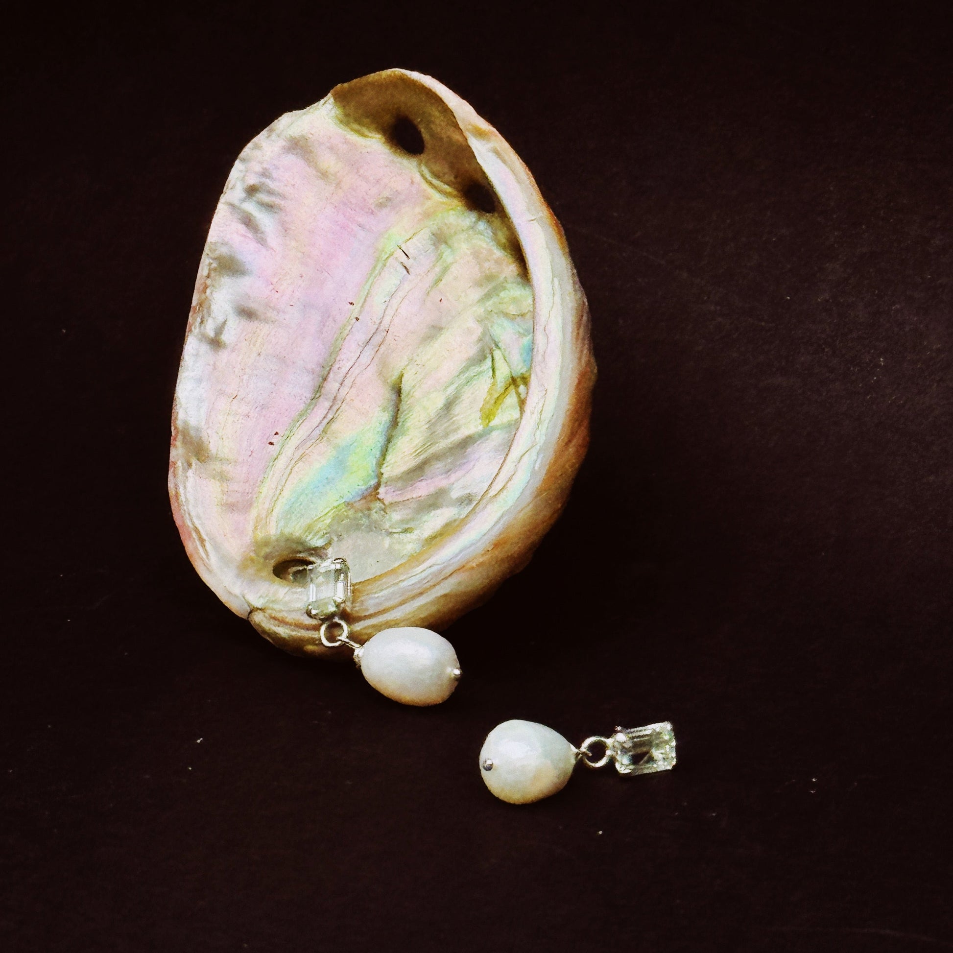 image of grace pearl studs on a black background resting on a shiny shell
