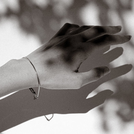 Black and white photo of a hand with a bracelet against a blurred background