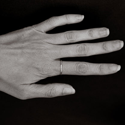 Black and white photo of a hand with a ring on a dark background