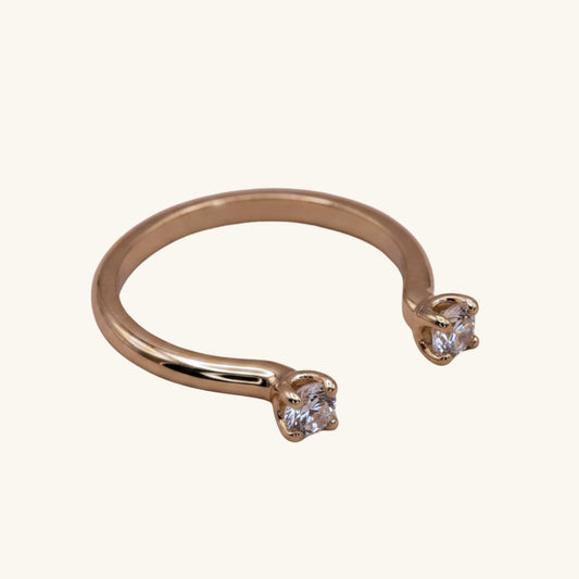 Gold open ring with two clear gemstones on a white background