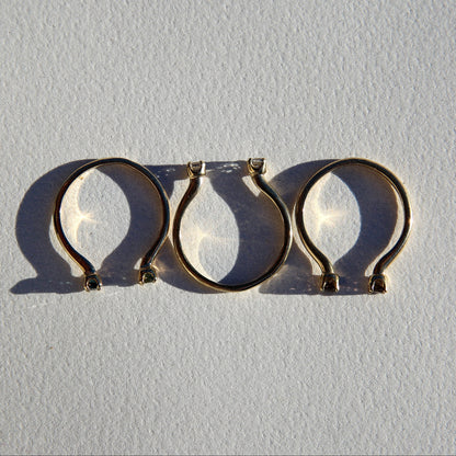Three gold hoop earrings on a light gray background