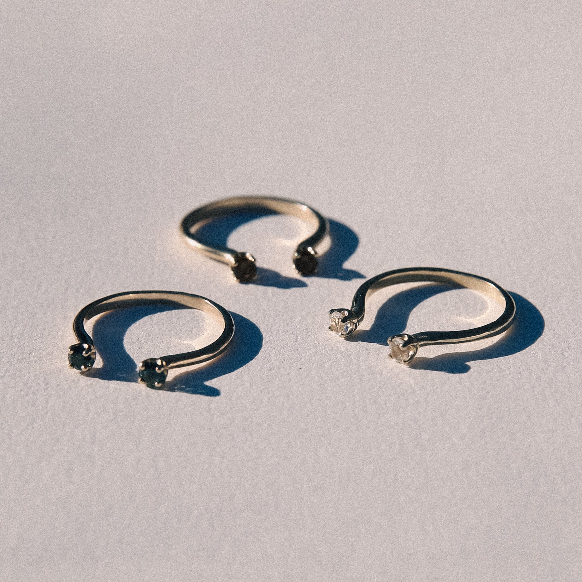 Three gold open rings on a light gray background