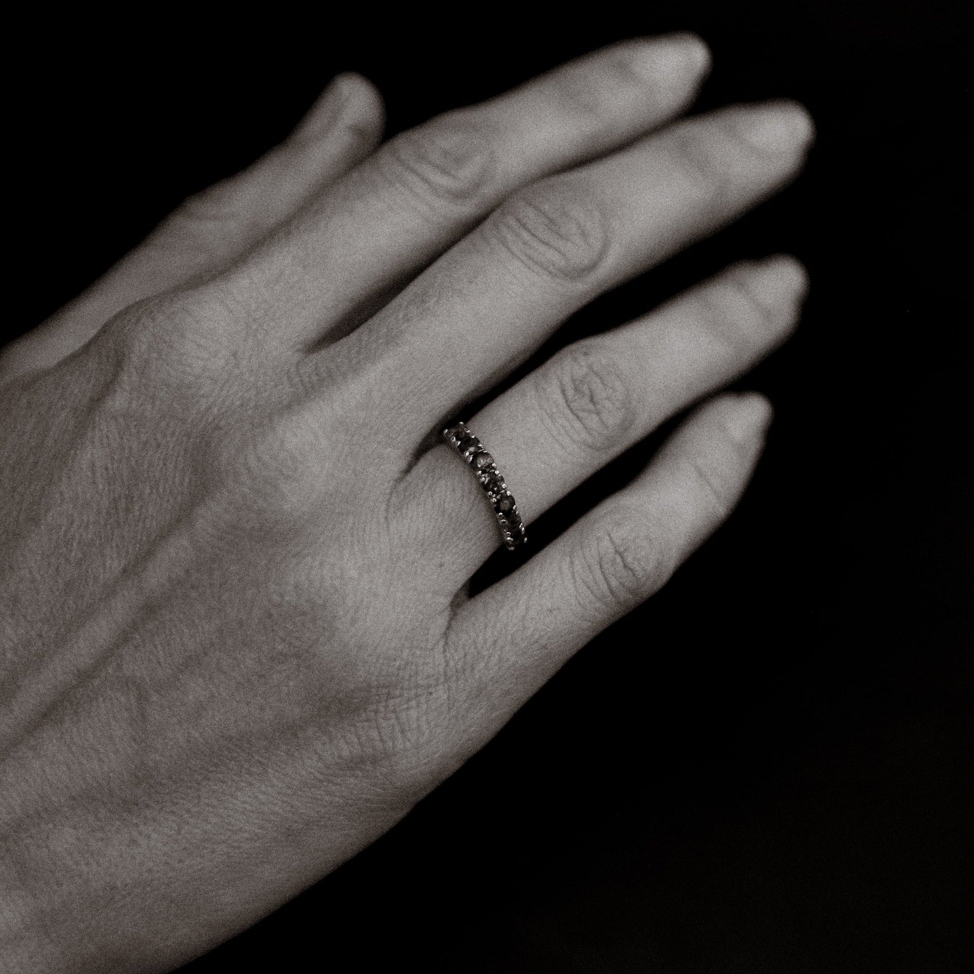 Hand wearing a ring on a black background