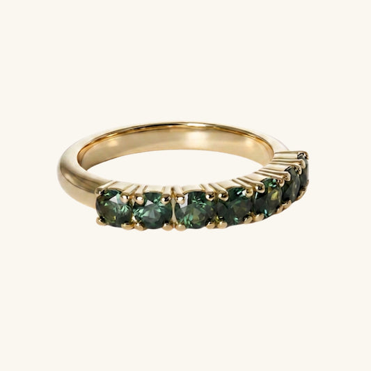 Gold ring with green gemstones on a white background