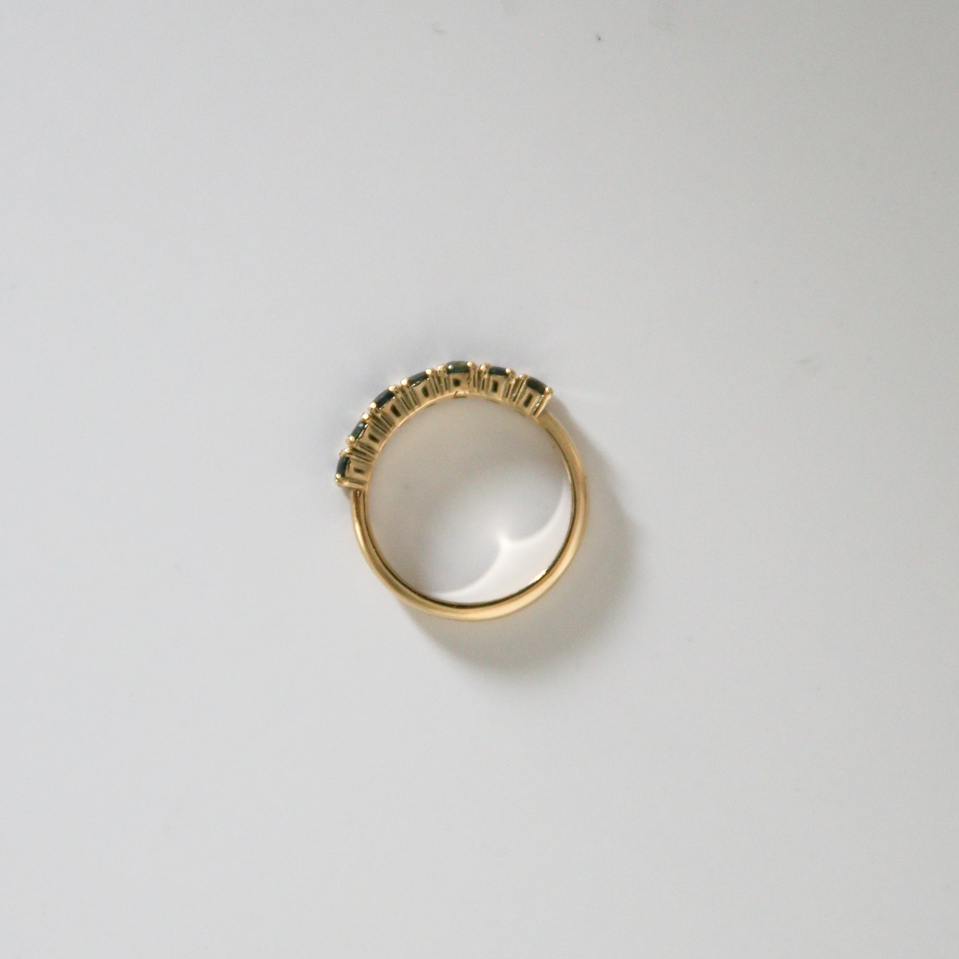 Gold ring with gemstones on a light gray background