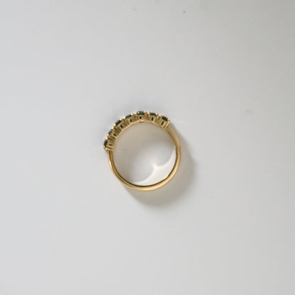 Gold ring with gemstones on a light gray background