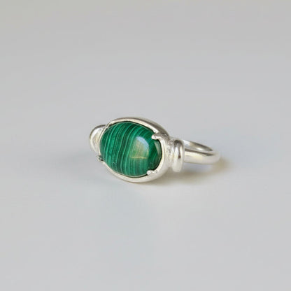 Silver ring with a green gemstone on a whitebackground