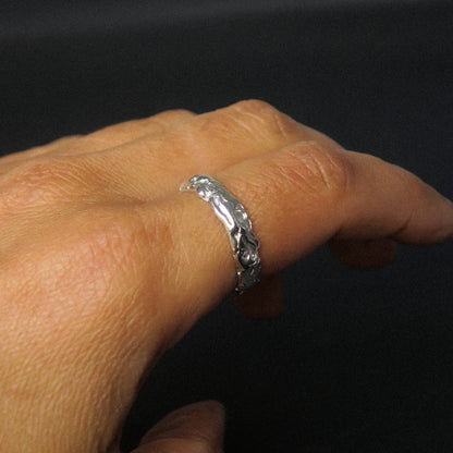 Silver ring on a person's finger against a black background