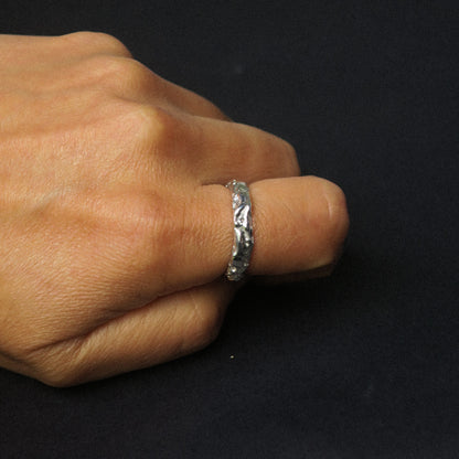 Silver ring on a finger against a black background
