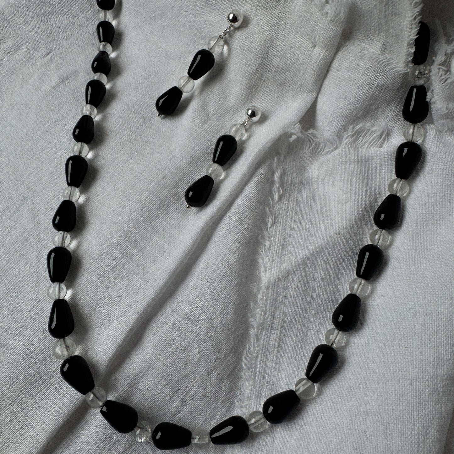 Necklace with black and clear beads on a light fabric background