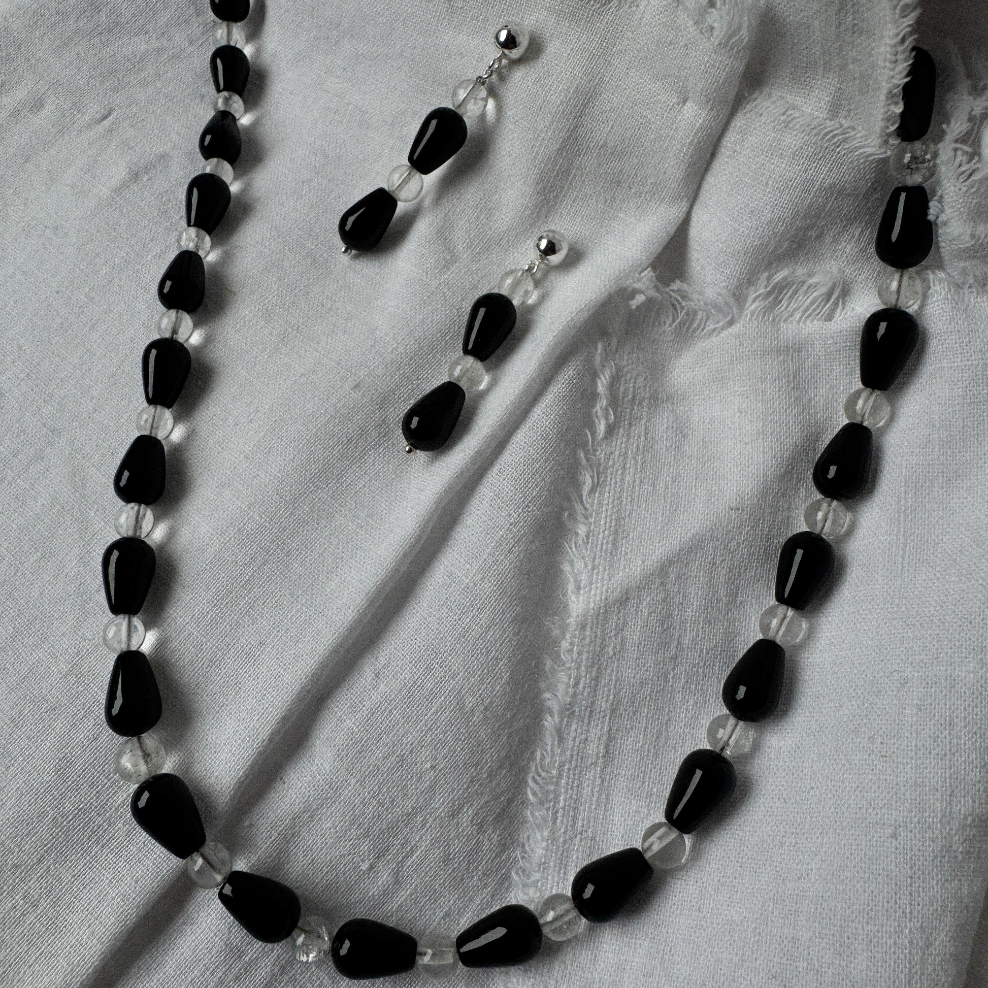 Necklace with black and clear beads on a light fabric background