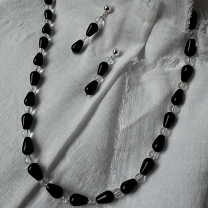 Necklace with black and clear beads on a light fabric background