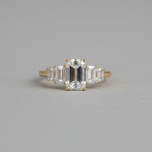 Diamond ring with emerald-cut gemstone on a gray background