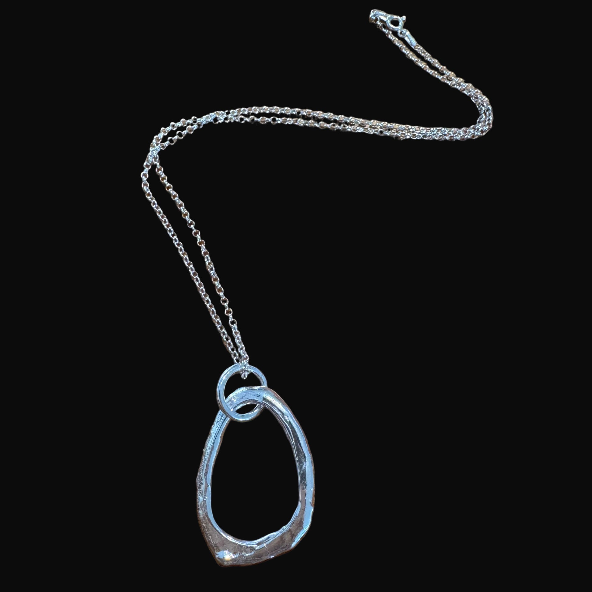 Silver necklace on a black surface