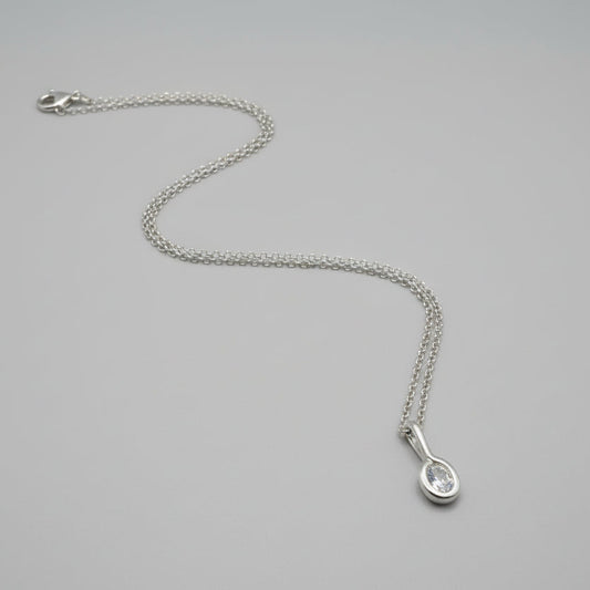 Silver necklace with a teardrop-shaped pendant on a gray background