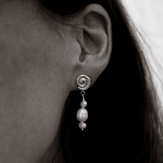 Close-up of an earring with a pearl drop on a blurred background