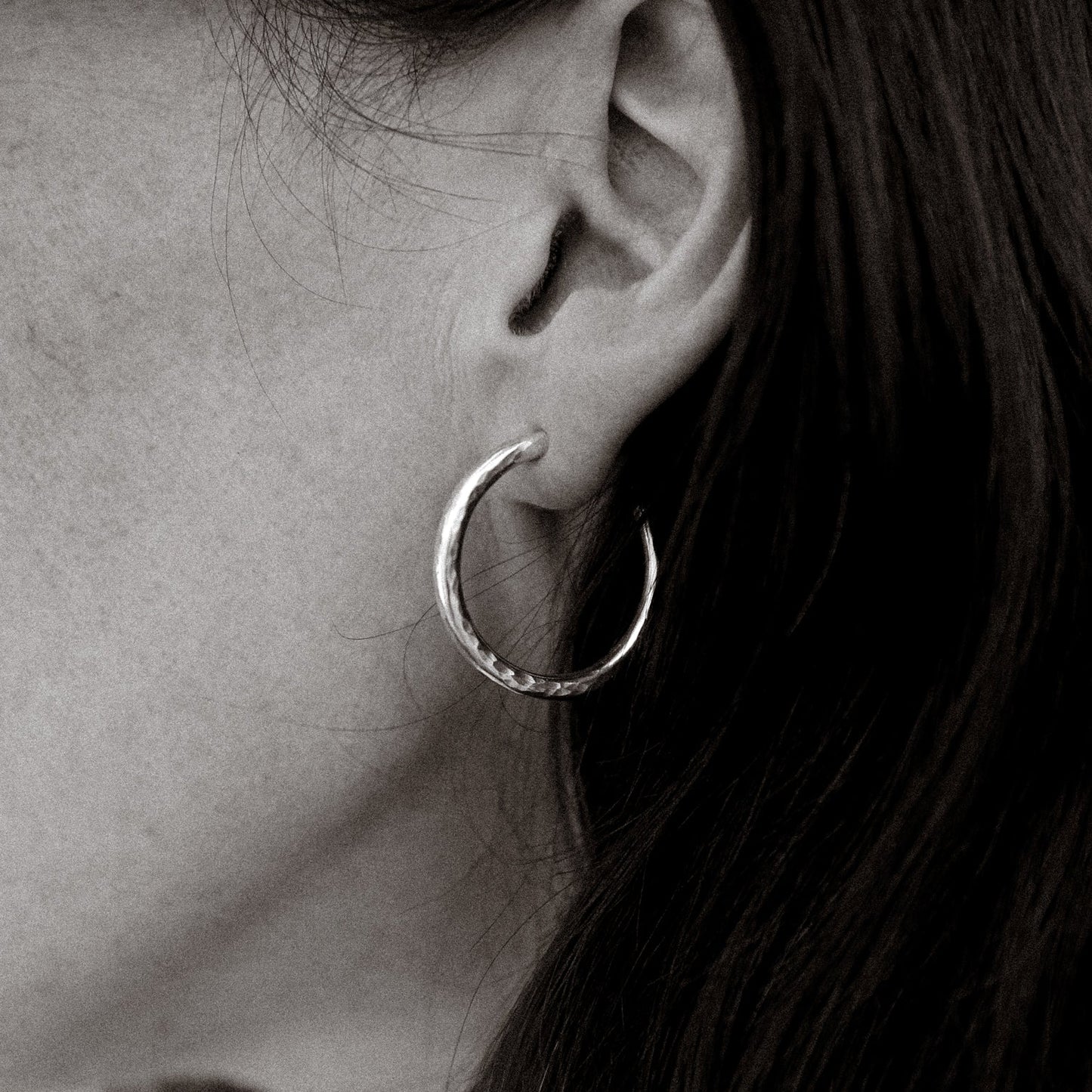 Close-up of a person wearing a hoop earring with a blurred background