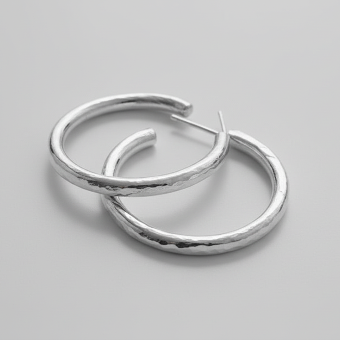 Pair of silver hoop earrings on a gray background